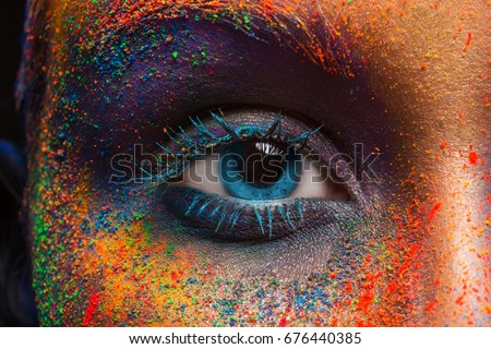 Crop of female eye with colorful make up. Beautiful fashion model with creative art makeup. Abstract colourful splash make-up. Holi festival Royalty-Free Stock Photo #676440385