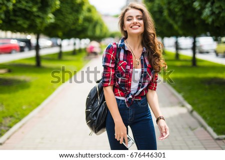 Street portrait of beautiful young woman walking in city street with backpack