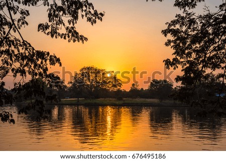 Silhouette of forest at sunset with reflection on water at Phutthamonthon in Thailand