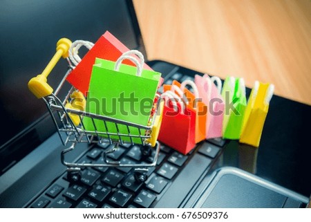 Model colorful shopping bag in trolley on laptop. Shopping at home or online internet shopping e-commerce idea concept.