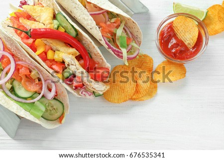 Stand with tasty fish tacos on white wooden background