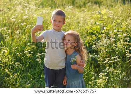  Happy family kids brother and sister taking selfie together. Kids making self portrait on smartphone in summer park. Selfie with the best friends