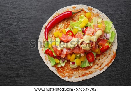 Fish taco with salmon and chili pepper on dark background