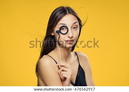 Beautiful young woman on a yellow background holds a paper accessory for parties.