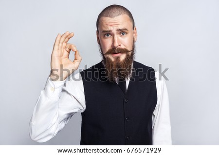 Agree. Handsome businessman with beard and handlebar mustache looking at camera with Ok sign. studio shot, on gray background.