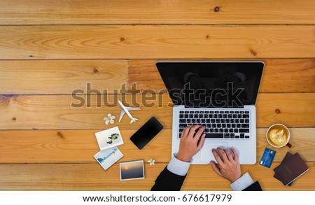 Man's using computer laptop and smartphone for financial transactions and shopping online. Online business. Top view of laptop, Smartphone, Credit card, Airplane etc. Business and E-commerce concept.