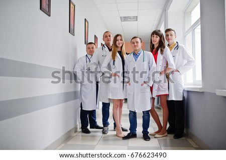 Group of young doctors in white coats posing in the hospital.
