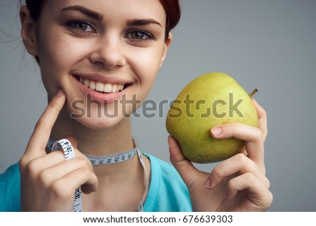 Woman with a measuring tape around her neck holding an apple portrait                               