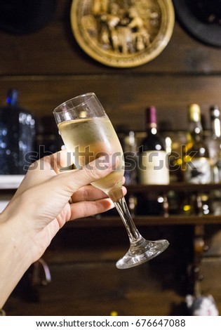 A glass of white wine in hand on a dark background