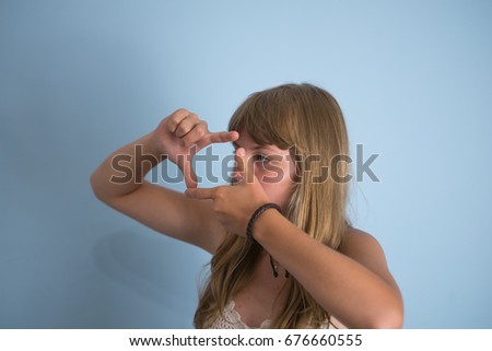 Closeup of young beautiful brunette woman making frame with her fingers, over gray background