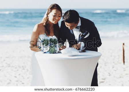 Asian wedding couple signs the papers standing on the beach
