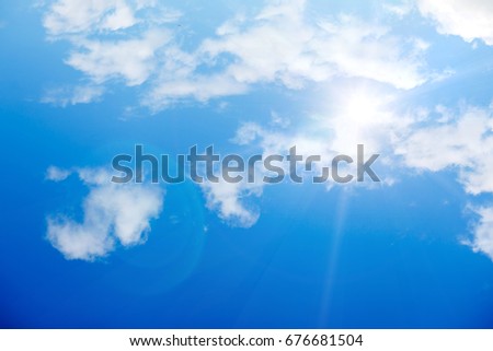 Bright sun with rays against a blue sky with white clouds
