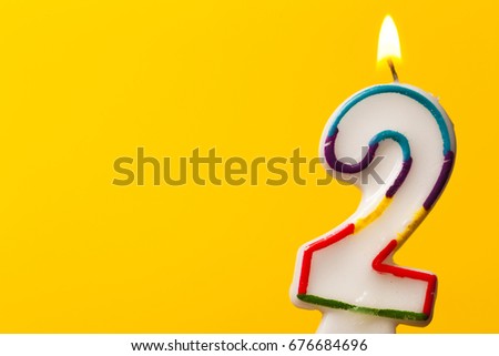 Number 2 birthday celebration candle against a bright yellow background Royalty-Free Stock Photo #676684696