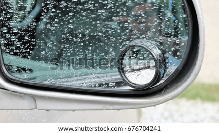 Car side mirror with rain drop at the surface in close up photo