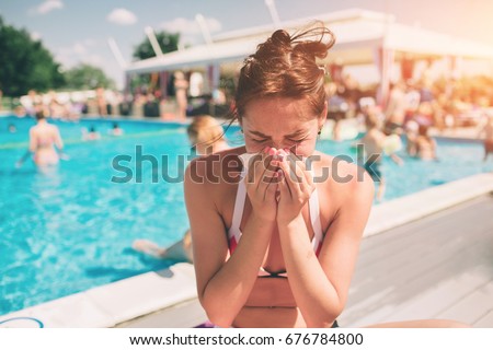 picture from a Beautiful women in bikini with handkerchief. Sick female model has runny nose. girl makes a cure for the common cold. She is sick in the summer on vacation