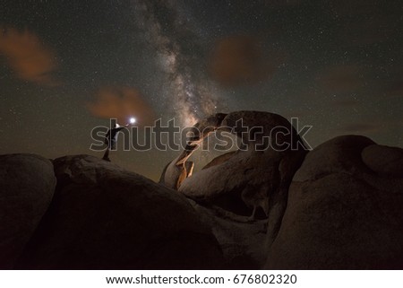 Man exploring Mobius Arch at night under the Milky Way Galaxy. 