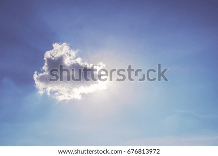 sun shining through one cloud in the blue sky on a hazy day