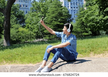 man sitting outdoors listening to music holding phone up