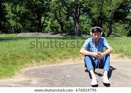 man sitting looking down at phone listening to music on phone 
