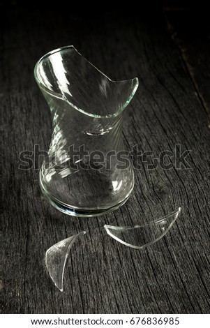 Broken glass glass and shards on a gray wooden background. Low key. Side view.