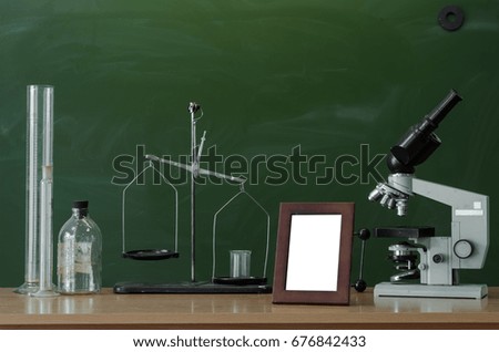 Teacher or student desk table. Education background. Education concept. Microscope, beakers, vials, photo frame and scales on the table. Chemistry or biology lesson.