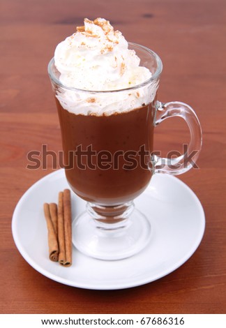 Hot chocolate with whipped cream and cinnamon in a mug on a wooden background