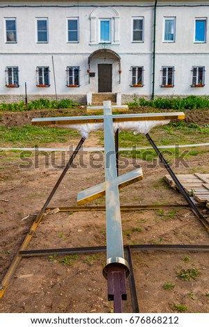 Giant Christian golden cross lies on a special stand near the house