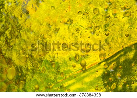 The photo a close up of abstract art glass of yellow color with impregnations of bubbles and spots .Glass abstract background. Pattern. Glass abstract. Modern Art  deco. Decor glass. 