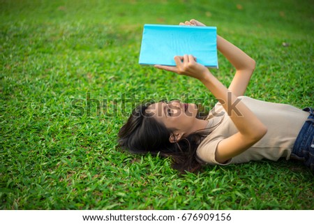 Asian young girl reading book on park in holidays