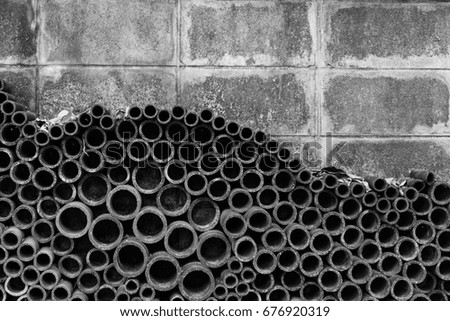 Differences size of ceramics pipes placed in curve pattern on the old brick background wall, black and white photograph in selective focus.