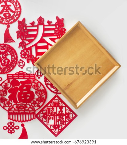 Chinese new year decorations and wooden empty tray text space background. "Spring","Prosperity" and "Lucky" words cut out from red paper. Traditional Chinese art and craft paper cutting.