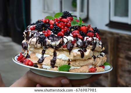 Hands holding pavlova Birthday cake covered with different kinds of fresh fruit