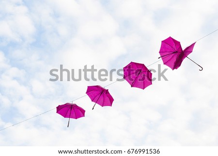 Pink umbrellas hanging from cables, symbolizing feminism