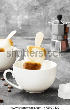 Coffee ice cream popsicles in white cups on a dark background
