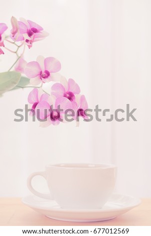 Coffee cup and beautiful purple orchid flowers on wood table over soft white background,pastel filter