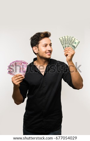 Handsome Indian/Asian man holding Paper currency notes (Rupees OR US Dollars), standing isolated over white background