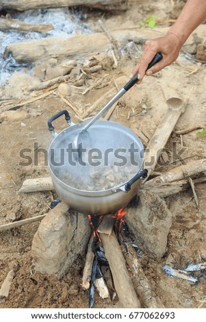 Man Cooking on campfire in forest.