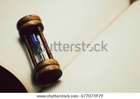 close up hourglass on paper book with copy space background, business concept, process vintage tone