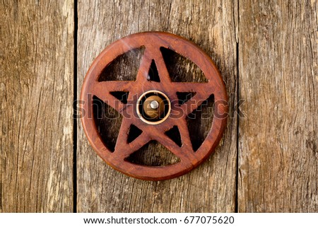 Wooden wiccan pentagram with incense burning - on wooden plank background