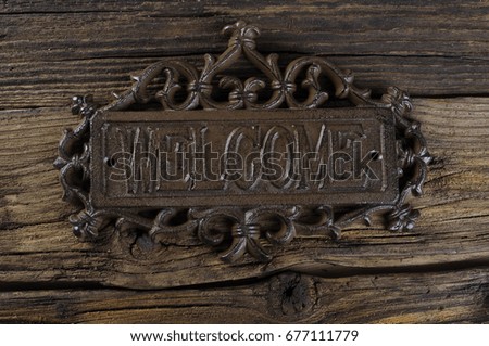 metal signboard with carved welcome monogram inscription 