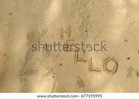 Handwriting  words "HELLO" on sand of beach.