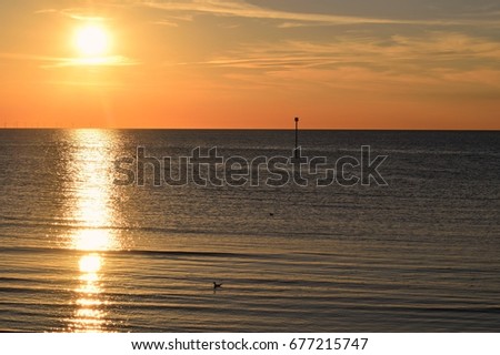 An orange sunset on a blue UK sea