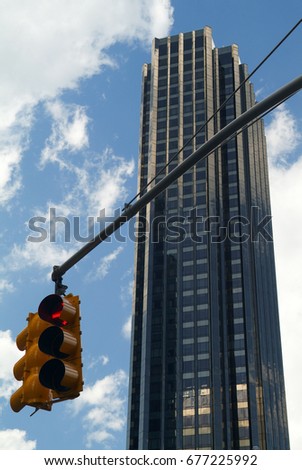 A Traffic light hanging from a pole against the background of a skyscraper