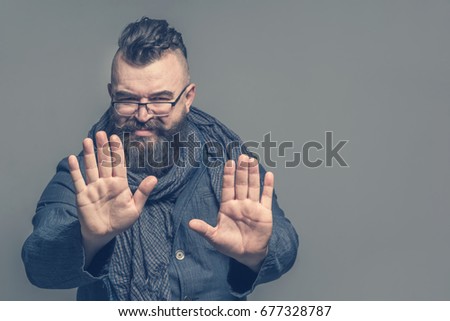 Adult bearded man with a mohawk hairstyle showing hands gesture stop