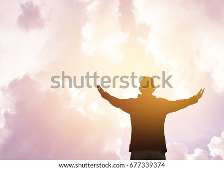 isolated of a man with wide spread arms and hands against cloudy sky and sun light worship and thank God heavenly father, christian worship concept