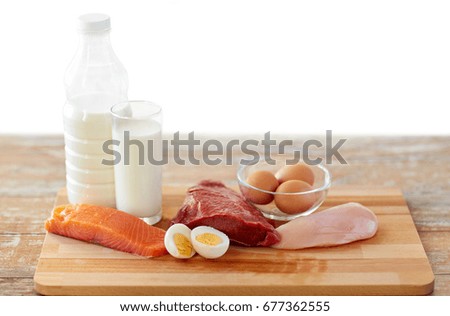 natural food, healthy eating and protein diet concept - raw meat fillet, fish, milk and eggs on wooden table Royalty-Free Stock Photo #677362555