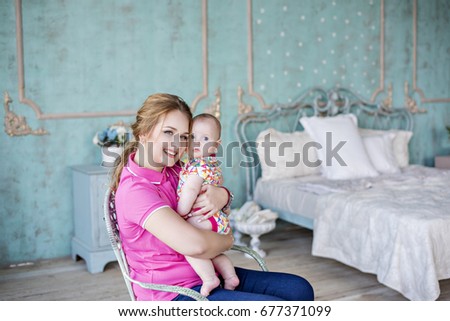 Beautiful young mother plays with her little daughter in her arms