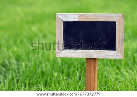 blank signboard stands on the green lawn