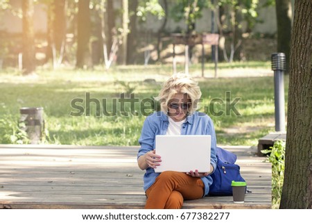 happy beautiful woman, girl with laptop surfing the web nearby lake