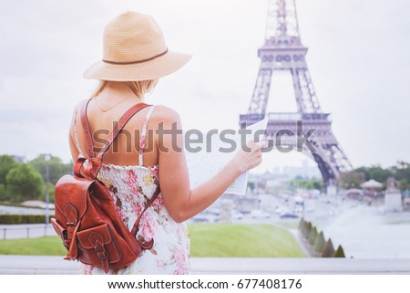 tourist looking at the map of city Paris near Eiffel tower, tourism in France